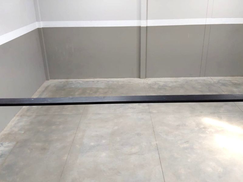 An empty utility or storage space featuring concrete flooring and two-tone painted walls with a metal safety railing.