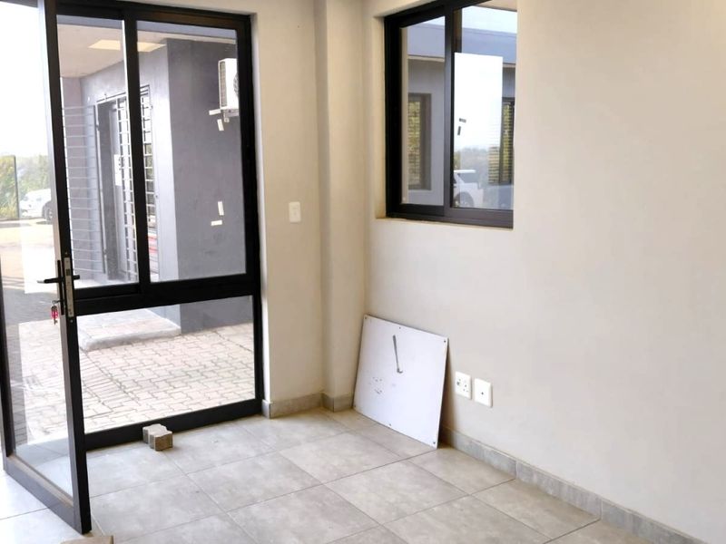 A clean, modern entrance area featuring tiled flooring, aluminium-framed glass doors, and neutral walls, providing a bright and professional welcome to the industrial space.
