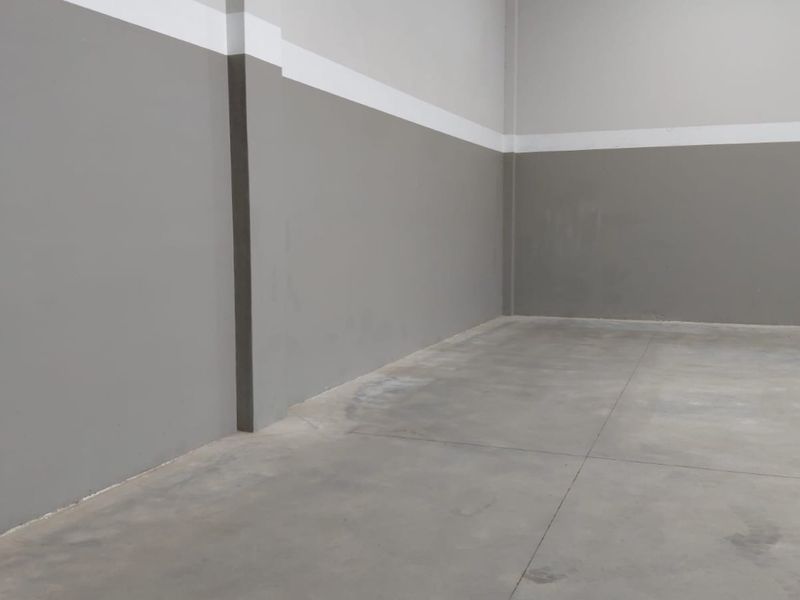 A clean, empty industrial utility space featuring smooth concrete flooring and freshly painted grey and white walls.