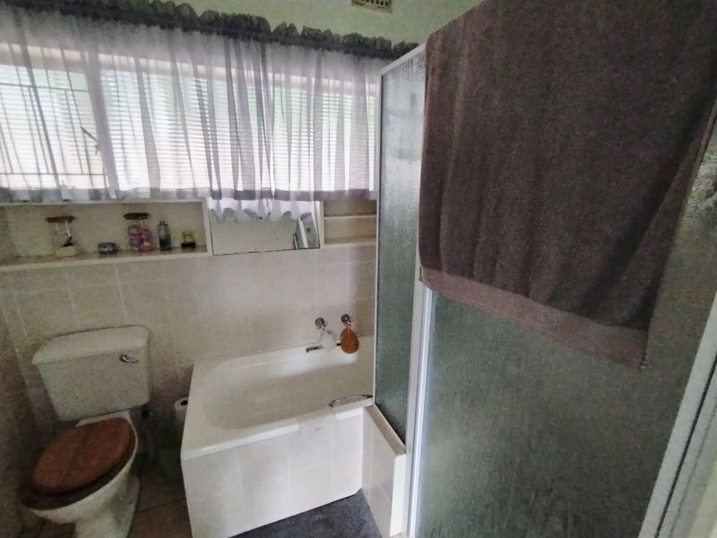 A functional bathroom featuring a built-in bathtub, separate shower enclosure, toilet, and integrated wall shelving with tiled finishes.
