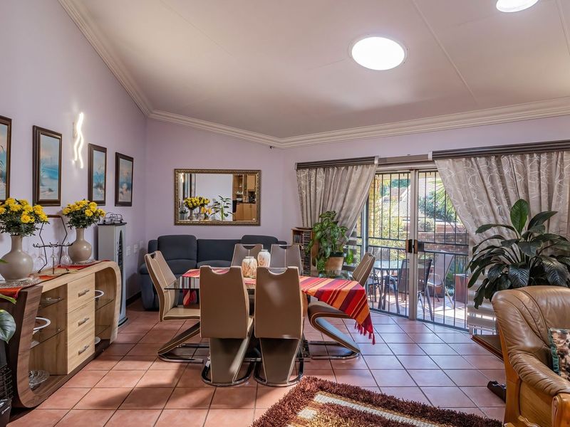 Spacious open-plan living and dining area featuring tiled flooring, a vaulted ceiling with a skylight, and sliding glass doors leading to an outdoor patio.