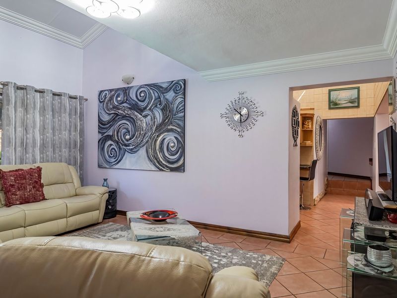 A spacious living room featuring vaulted ceilings with crown molding, ceramic tile flooring, and a sliding glass door providing natural light.