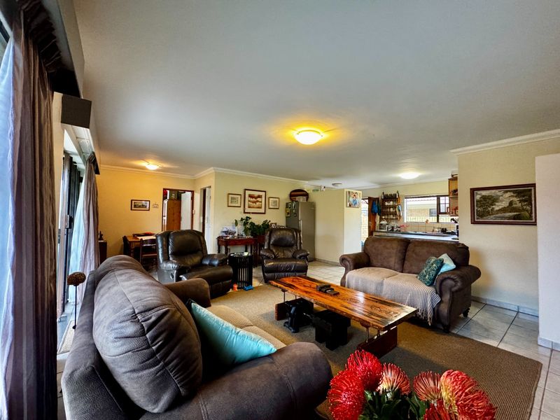 Spacious open-plan living and dining area featuring tiled floors, coved ceilings, and direct access to the outdoors through sliding glass doors.