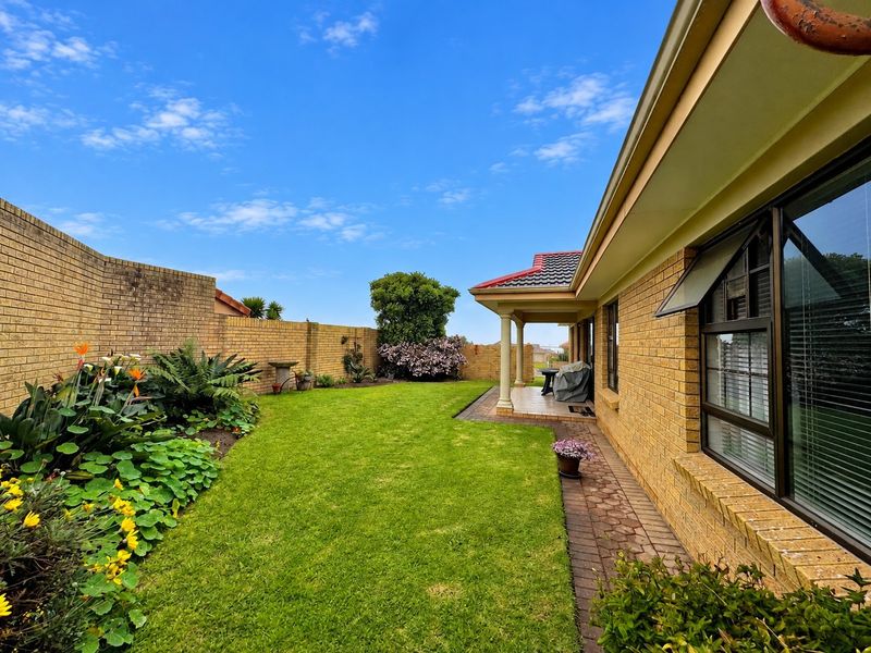 A well-maintained rear garden featuring a paved patio, covered veranda, and established brick boundary walls, providing a private outdoor living space.