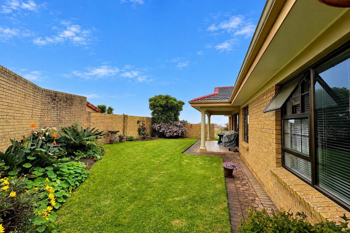 A well-maintained rear garden featuring a paved patio, covered veranda, and established brick boundary walls, providing a private outdoor living space.