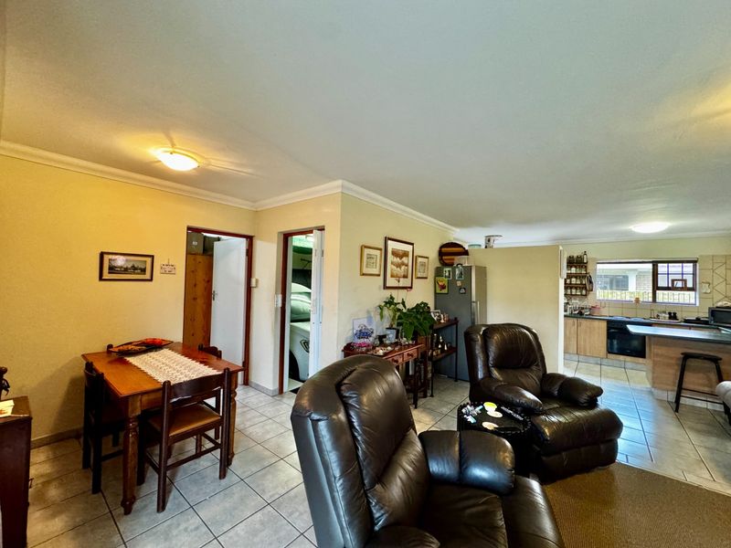 Open plan living and dining area featuring tiled flooring and a functional kitchen with built-in cabinetry and appliances.