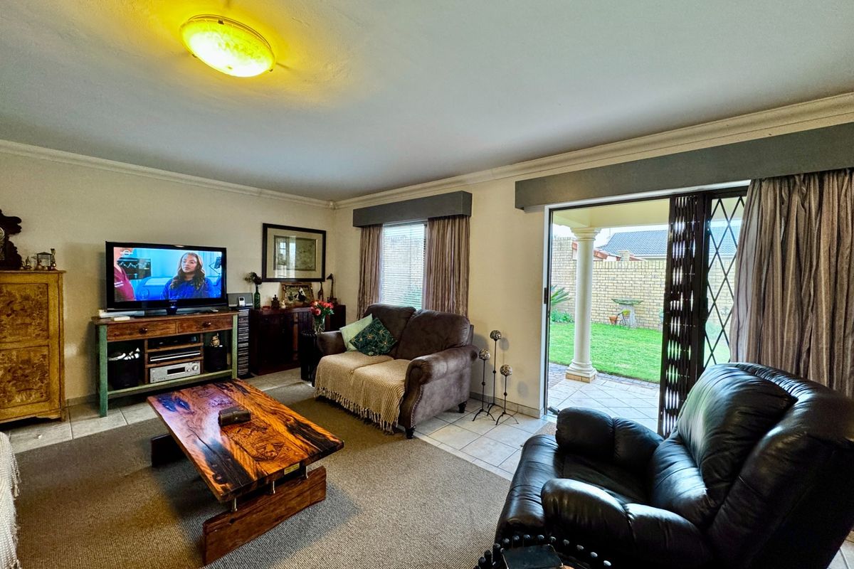 A comfortable living room featuring tiled flooring, a ceiling light fixture, and a sliding glass door providing direct access to the rear patio and garden.