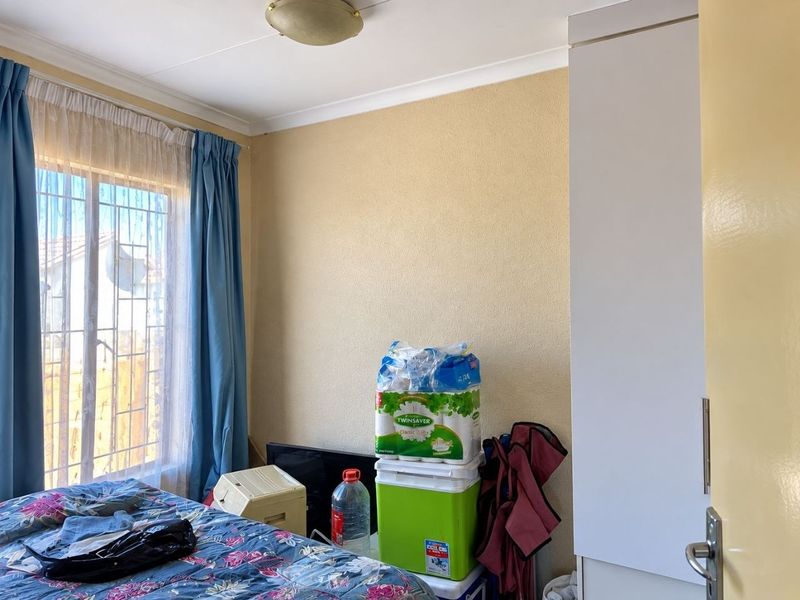 A bedroom featuring a built-in wardrobe, security gate on the window, and standard ceiling finishes.