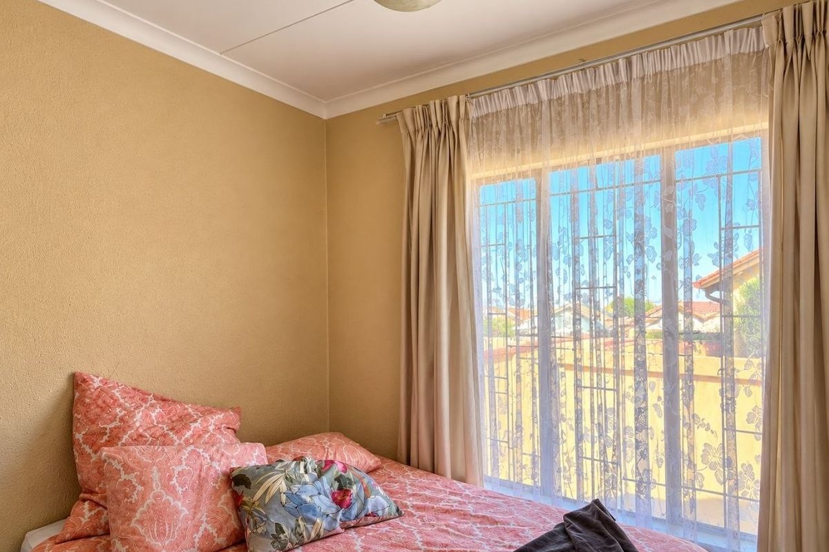 A bedroom featuring a large window with security bars, coved ceilings, and neutral wall finishes.