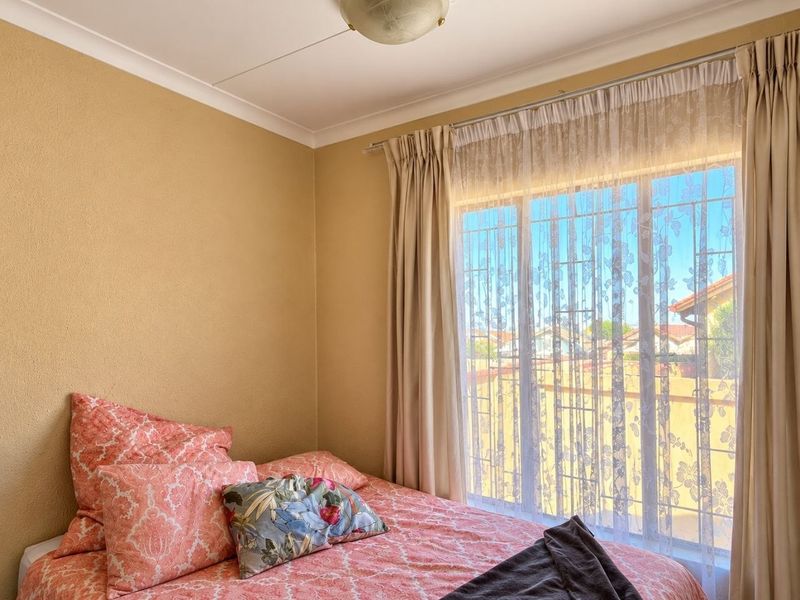 A bedroom featuring a large window with security bars, coved ceilings, and neutral wall finishes.