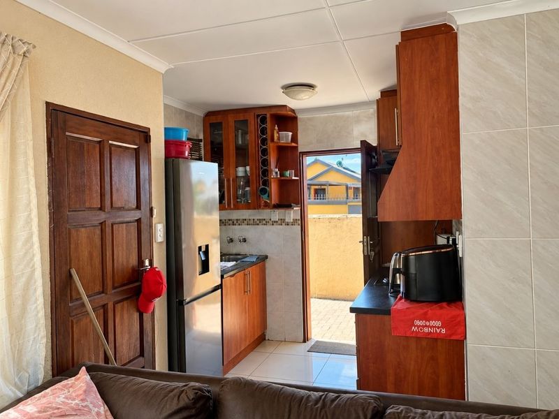 A functional kitchen featuring wooden cabinetry, tiled backsplash, and direct access to an outdoor area, providing a practical layout for daily use.