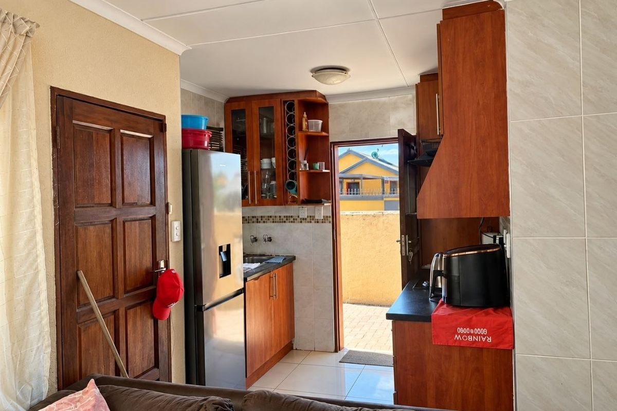 A functional kitchen featuring wooden cabinetry, tiled backsplash, and direct access to an outdoor area, providing a practical layout for daily use.