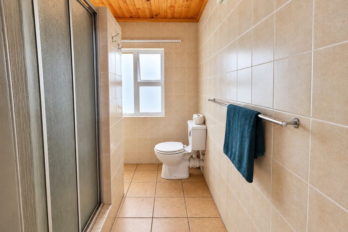 A functional bathroom featuring a shower enclosure, toilet, tiled finishes, and a timber-paneled ceiling.