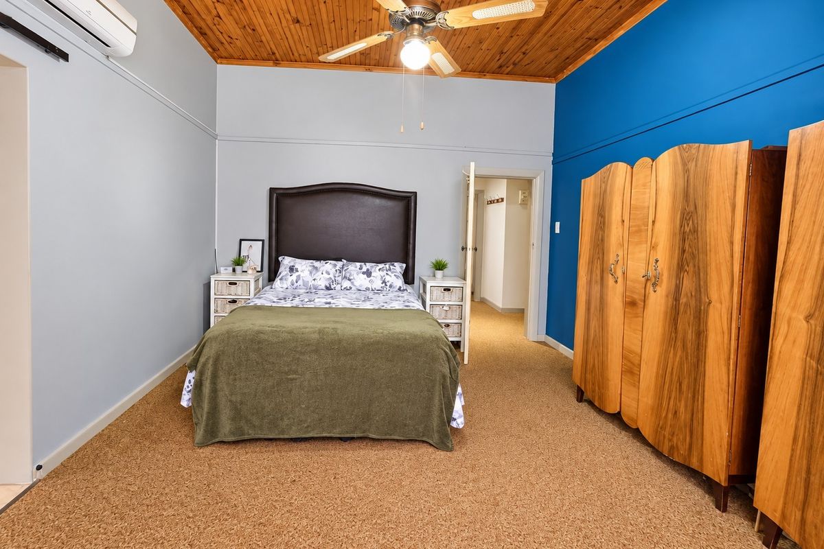 Spacious bedroom featuring a timber-paneled ceiling, ceiling fan, and split-system air conditioning unit.