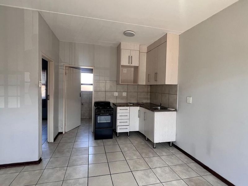 A functional kitchen area featuring tiled flooring, built-in cabinetry, a tiled backsplash, and a freestanding stove, offering a clean and practical layout.