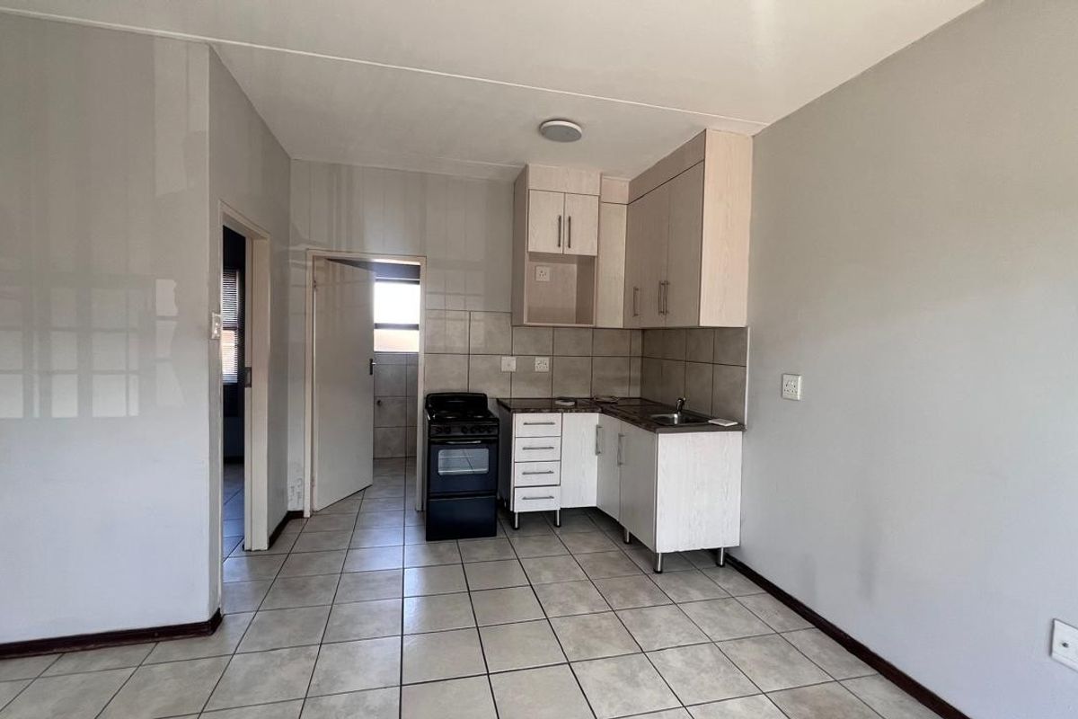 A functional kitchen area featuring tiled flooring, built-in cabinetry, a tiled backsplash, and a freestanding stove, offering a clean and practical layout.