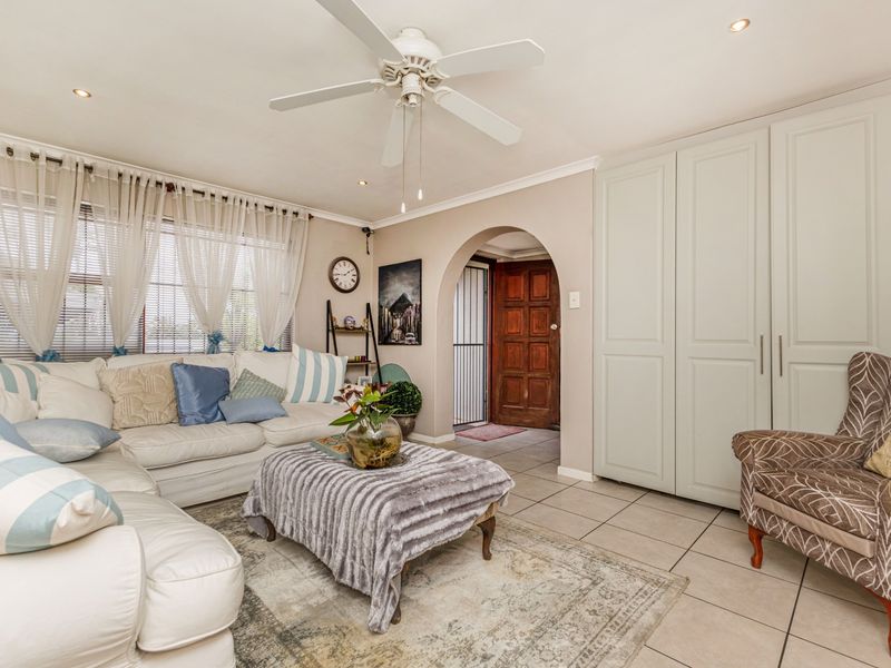 A comfortable living room featuring tiled flooring, a ceiling fan, recessed lighting, and built-in cabinetry, with an arched entryway leading to the front door.