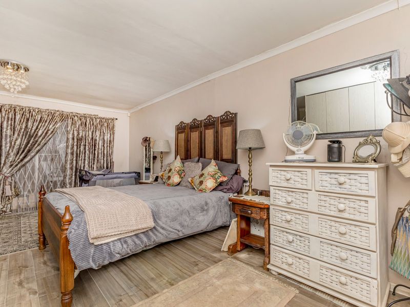 A spacious bedroom featuring tiled flooring, cove cornicing, and built-in cupboard storage, offering a comfortable and functional living space.