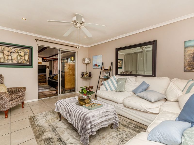 A comfortable living room featuring tiled flooring, a ceiling fan, and a sliding glass door providing access to an adjacent space.