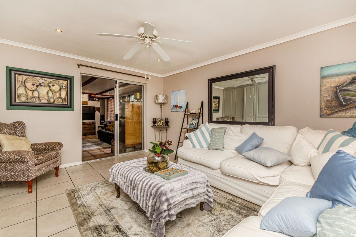 A comfortable living room featuring tiled flooring, a ceiling fan, and a sliding glass door providing access to an adjacent space.