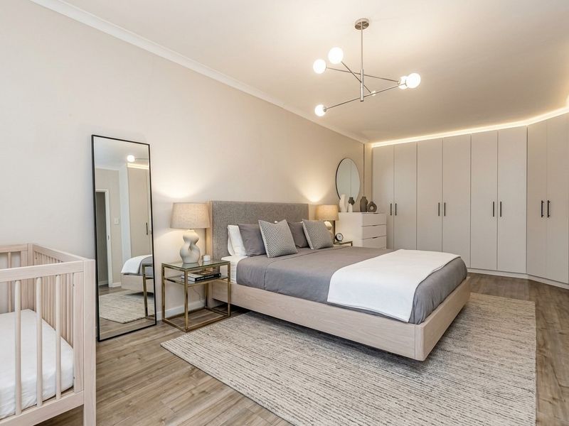 A well-appointed bedroom featuring extensive built-in cabinetry, modern recessed lighting, a contemporary chandelier, and high-quality laminate flooring.
