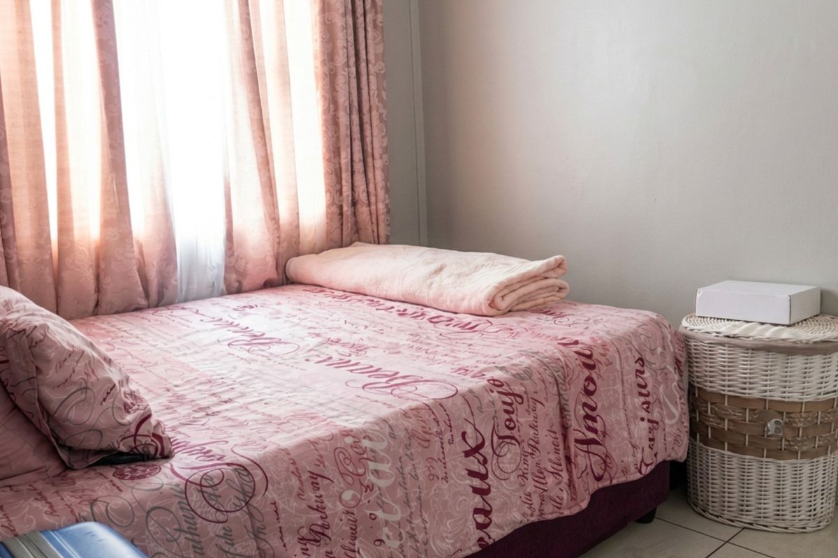 A bedroom featuring tiled flooring and natural light from a window with curtains.