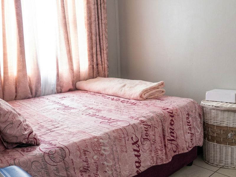 A bedroom featuring tiled flooring and natural light from a window with curtains.