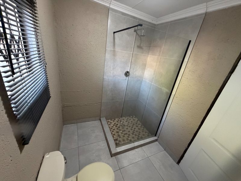 A clean, modern bathroom featuring a walk-in shower with a glass screen, tiled flooring, and neutral wall finishes.