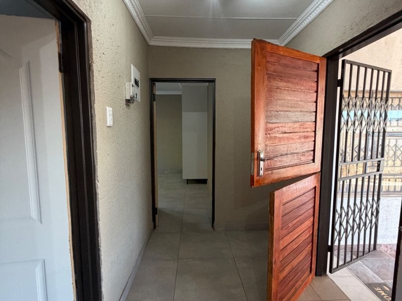 An entrance hallway featuring tiled flooring, decorative cornice, and a wooden stable door with an external security gate.