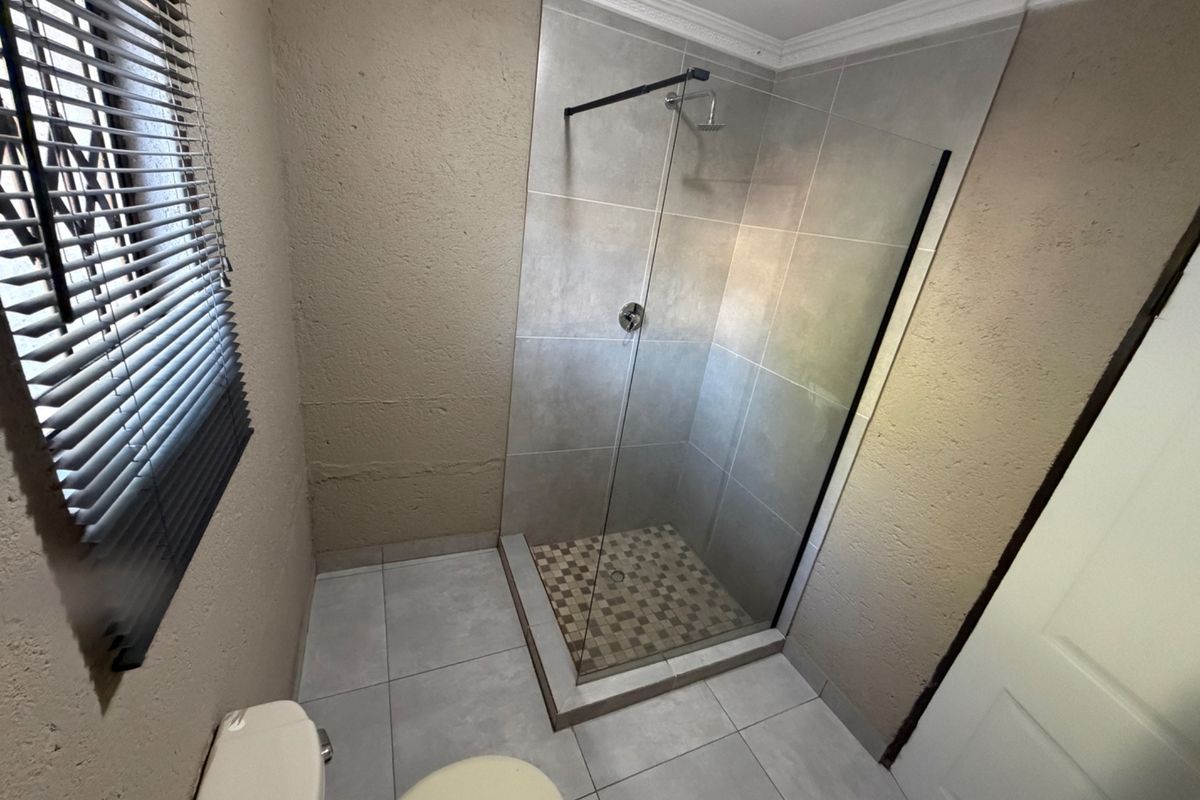 A clean, modern bathroom featuring a walk-in shower with a glass screen, tiled flooring, and neutral wall finishes.