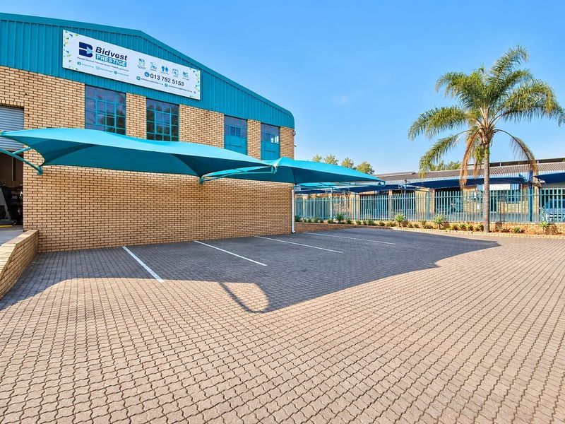 Commercial property exterior featuring a paved parking area with shade cloth carports and brick facade construction.