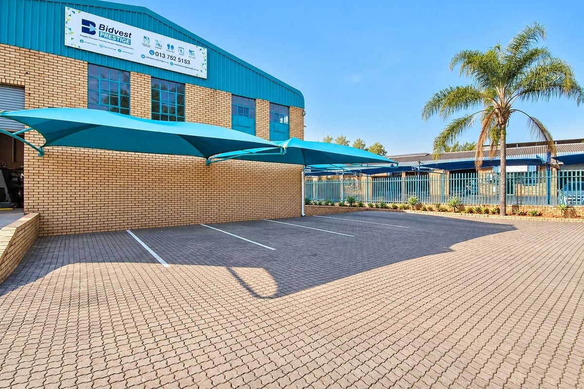 Commercial property exterior featuring a paved parking area with shade cloth carports and brick facade construction.