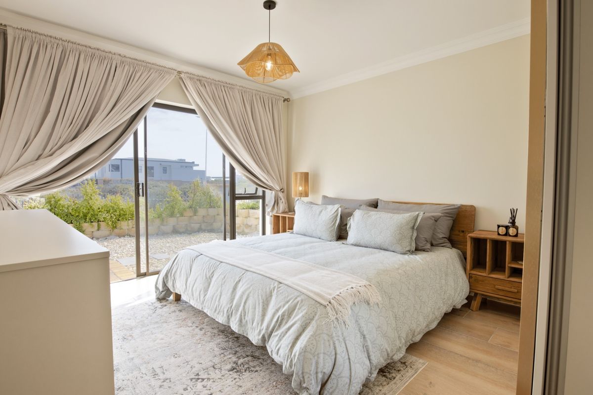 A bright and well-maintained bedroom featuring laminate flooring, cove cornicing, and large sliding glass doors that provide direct access to an outdoor patio area.