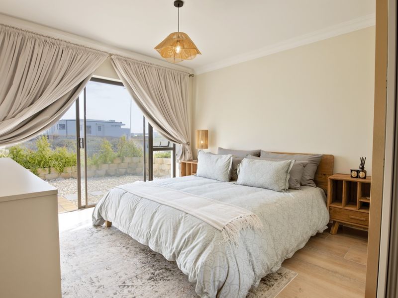 A bright and well-maintained bedroom featuring laminate flooring, cove cornicing, and large sliding glass doors that provide direct access to an outdoor patio area.