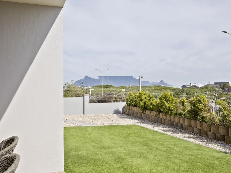 A well-maintained garden area featuring artificial lawn, gravel landscaping, and a retaining wall, offering scenic mountain views.