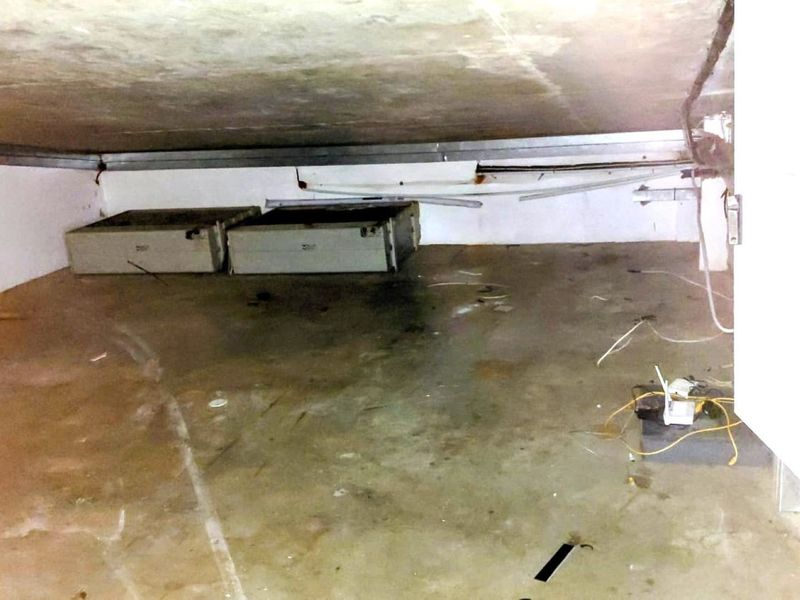 A low-ceilinged utility or storage space featuring a concrete floor and exposed electrical wiring, suitable for basic storage or infrastructure access.