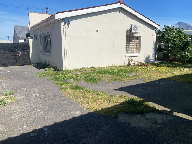 Rear exterior view of the property featuring an asphalt driveway, security bars on windows, and an external air conditioning unit.