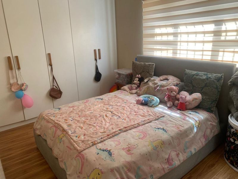 A well-maintained bedroom featuring built-in cupboards, laminate flooring, and adjustable roller blinds for natural light control.