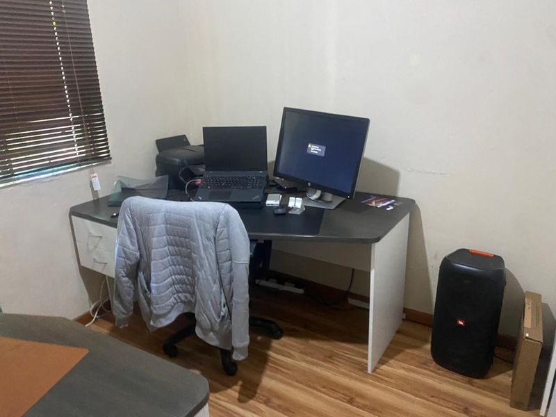 A functional home office space featuring laminate flooring and venetian blinds, providing a dedicated area for work or study.