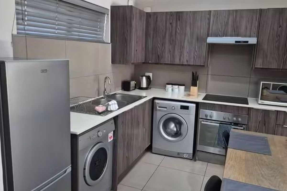 Modern kitchen featuring dark wood-grain cabinetry, integrated appliances, tiled splashbacks, and a functional layout with ample storage and counter space.