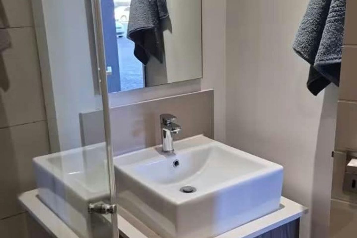 Modern bathroom featuring a vessel sink with a vanity cabinet, chrome mixer tap, and a glass shower screen.