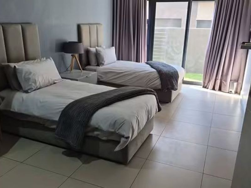 A well-maintained bedroom featuring tiled flooring, a built-in wardrobe, and a sliding glass door providing access to the exterior.