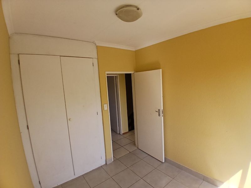 An empty bedroom featuring tiled flooring and built-in cupboards, offering a blank canvas for renovation or interior design updates.