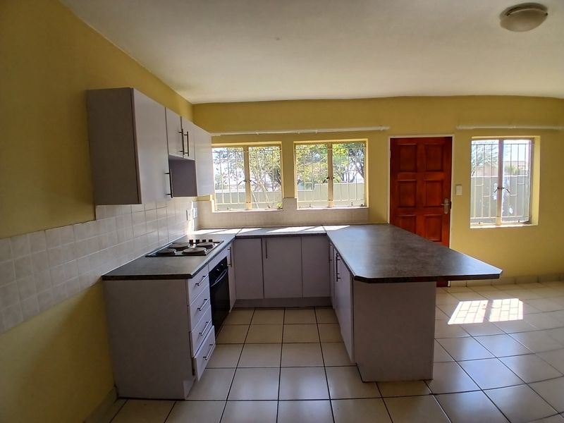 A functional kitchen featuring built-in cabinetry, an electric hob, oven, and tiled flooring, offering a clean and practical layout for renovation.