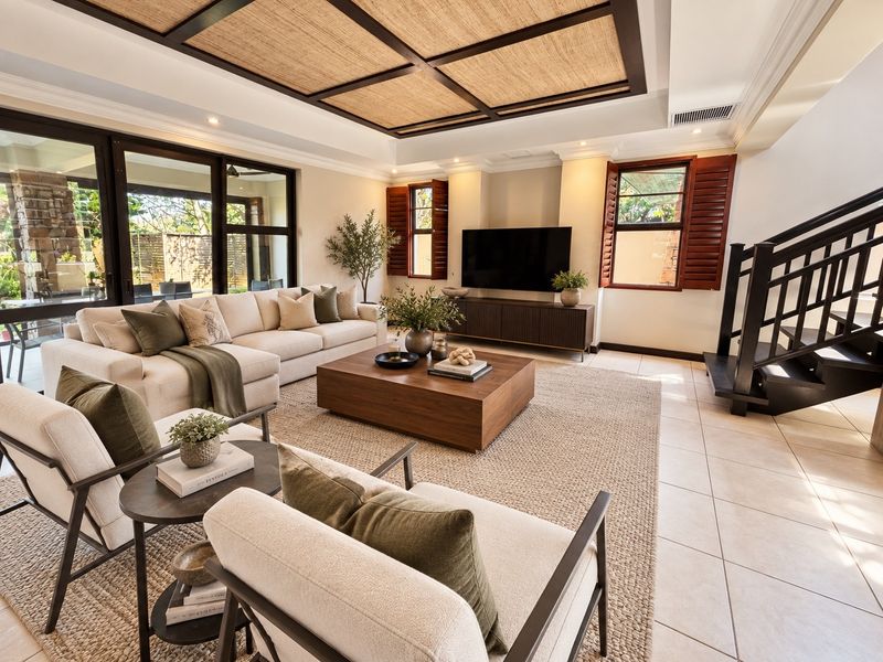 Spacious living room featuring a coffered ceiling, tiled flooring, ducted air conditioning, and large sliding glass doors leading to an outdoor patio area.