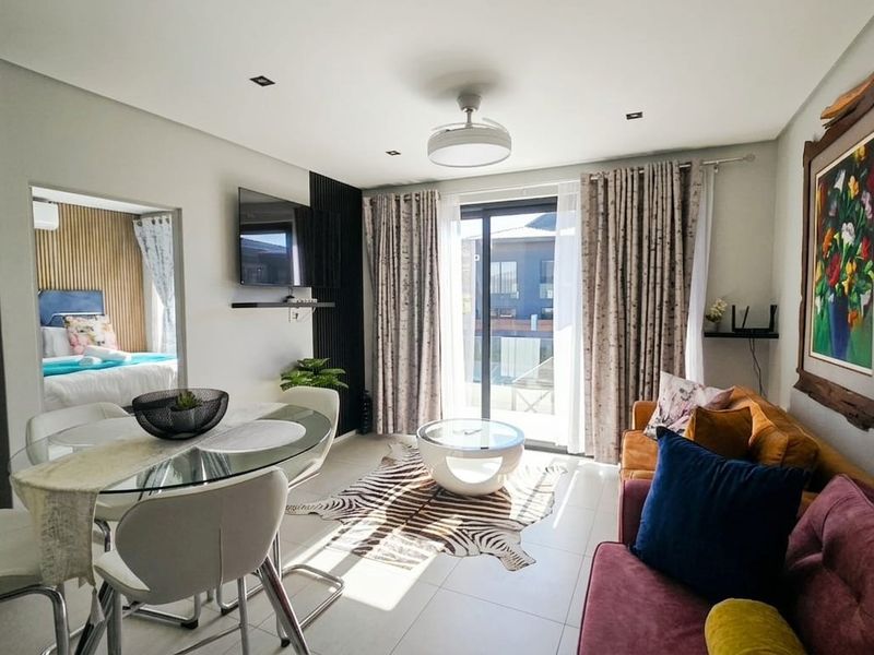 Bright open-plan living and dining area featuring tiled floors, recessed lighting, and a sliding glass door providing access to the exterior.