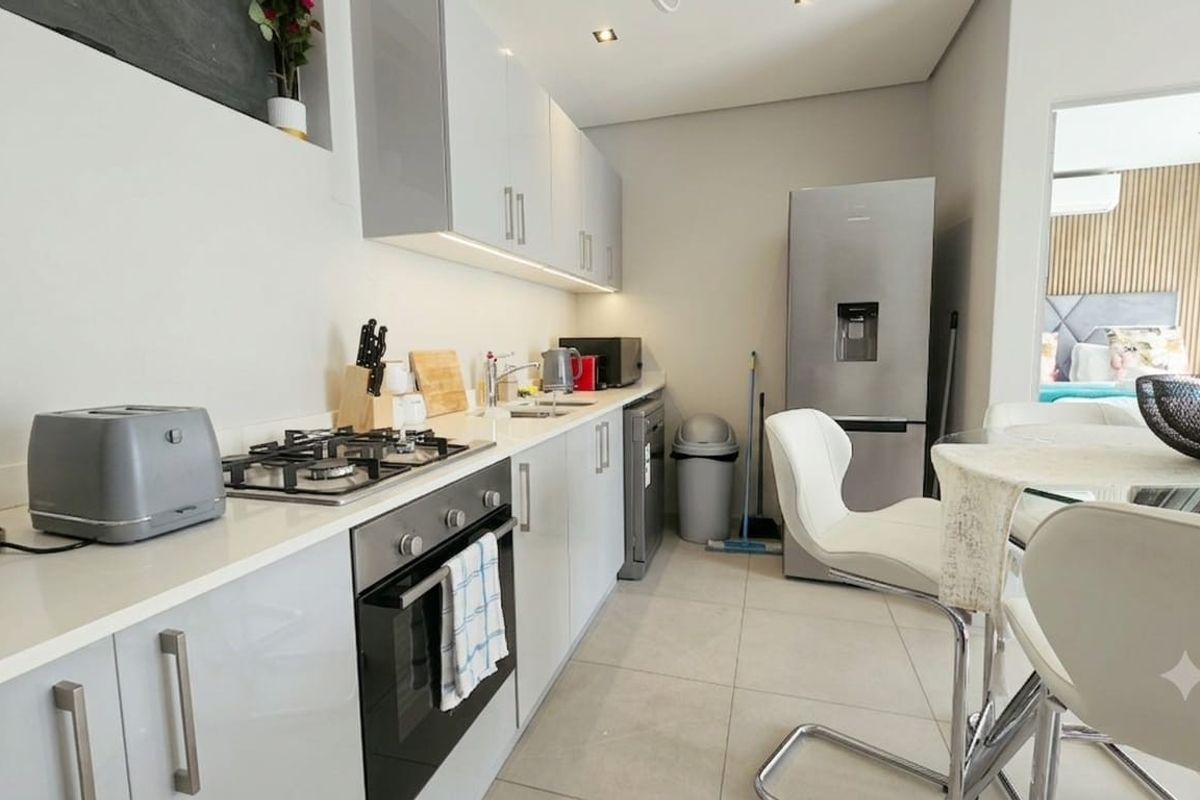 Modern kitchen featuring sleek high-gloss cabinetry, integrated gas hob, electric oven, and tiled flooring, offering a clean and functional culinary space.
