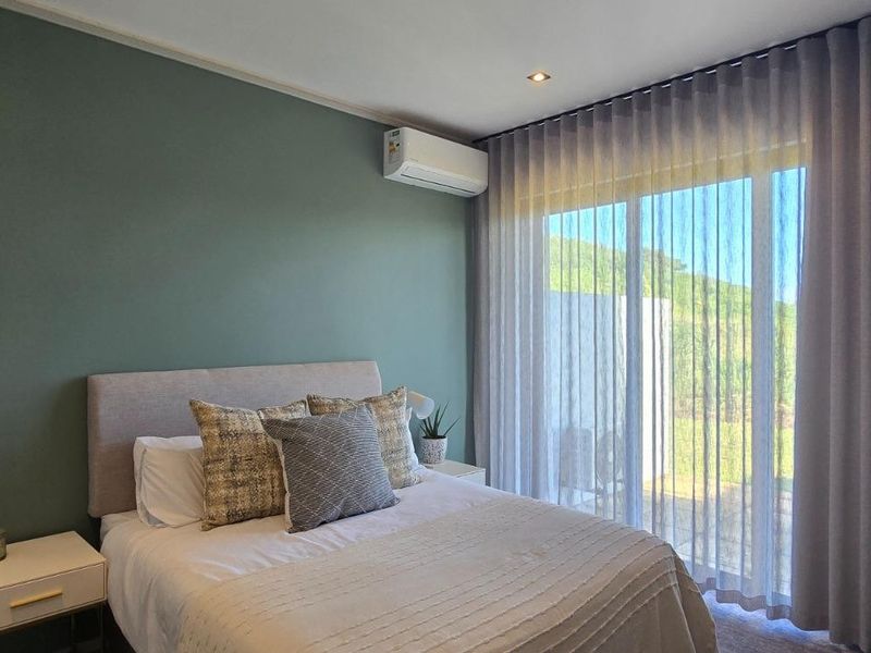 A well-maintained bedroom featuring a feature wall, air conditioning unit, and large sliding glass doors that provide natural light and outdoor access.
