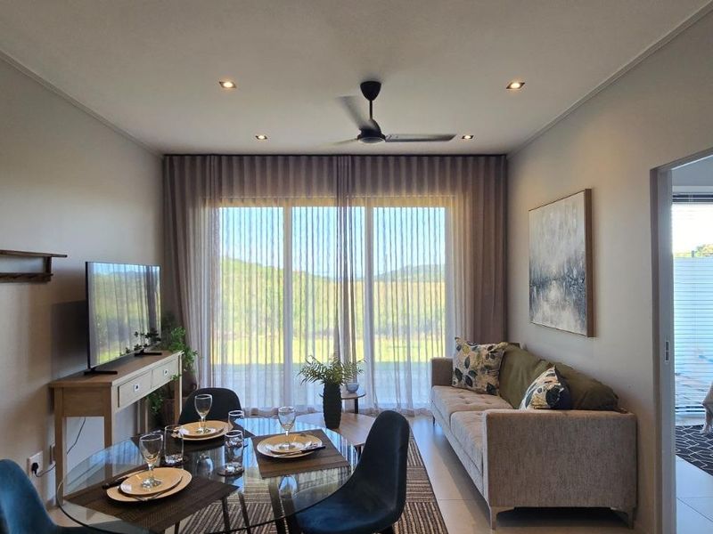 A well-maintained open-plan living and dining area featuring tiled floors, recessed lighting, a ceiling fan, and large sliding doors leading to an outdoor space.
