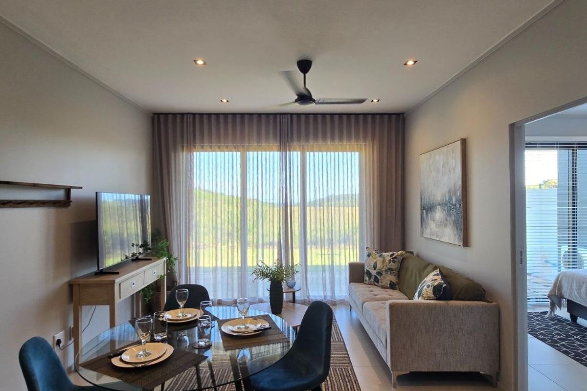A well-maintained open-plan living and dining area featuring tiled floors, recessed lighting, a ceiling fan, and large sliding doors leading to an outdoor space.